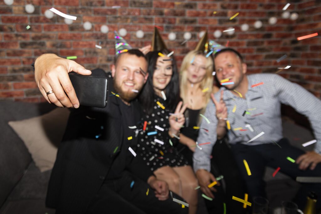 Gruppe tager selfie til en firmafest med festhatte og konfetti