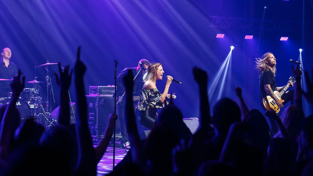 Stagebreakers på scenen i lilla lys med hænder i vejret