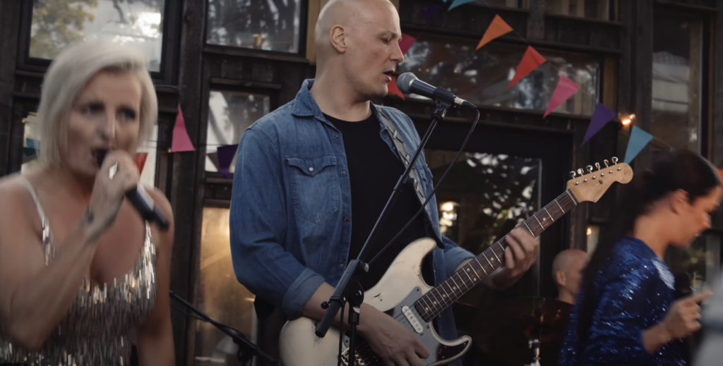 Sangerinde og guitarist fra SKRÅÅL ved udendørs bar