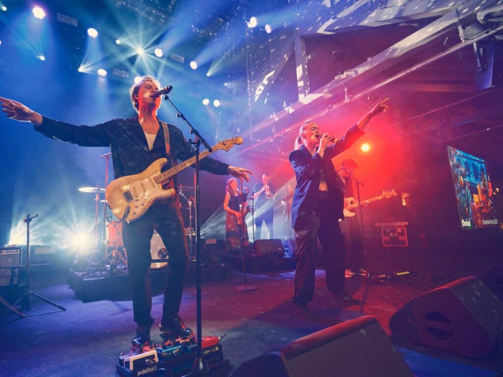 HouseKeepers på scenen i blåt og rødt lys med guitarist