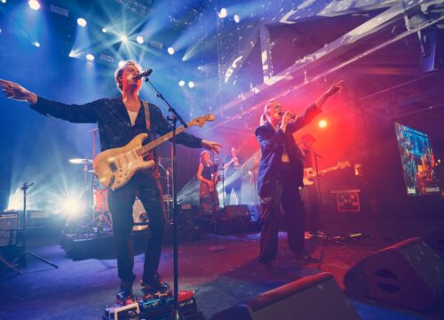 HouseKeepers på scenen i blåt og rødt lys med guitarist