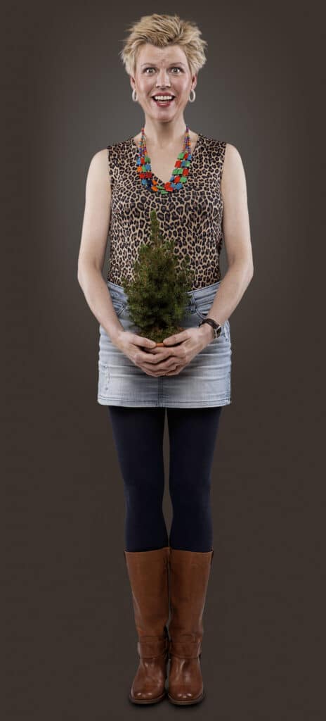 Rejsevennerne-figur står med en lille potteplante, helkropsbillede
