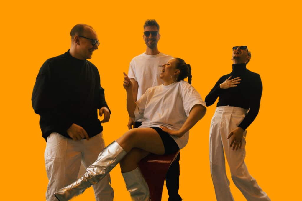 A-Live Band poserer leende foran orange baggrund