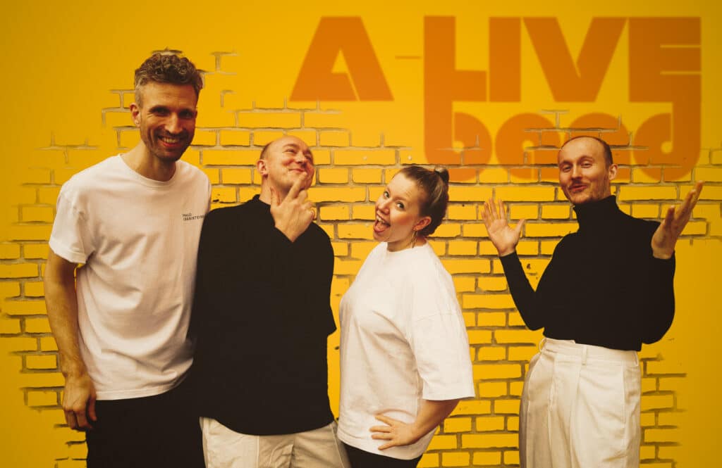 A-Live Band foran orange mur med bandets logo