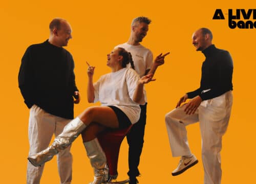 A-Live Band, fire musikere poserer energisk foran orange væg
