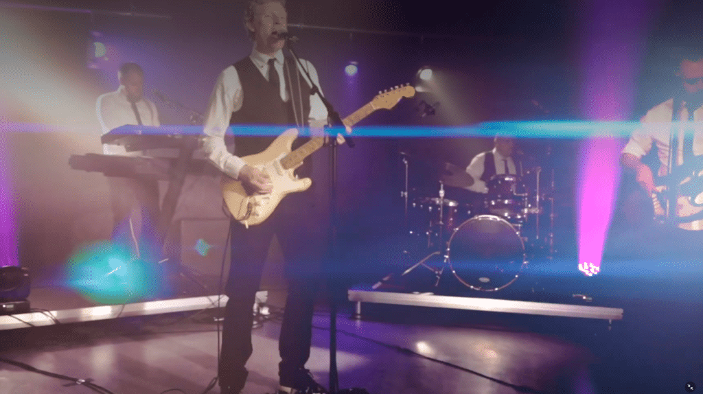 Jungle Fever på scenen i farverigt lys med keyboard og guitar